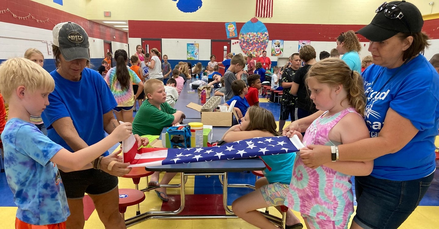 Teachers help students fold US Flag properly